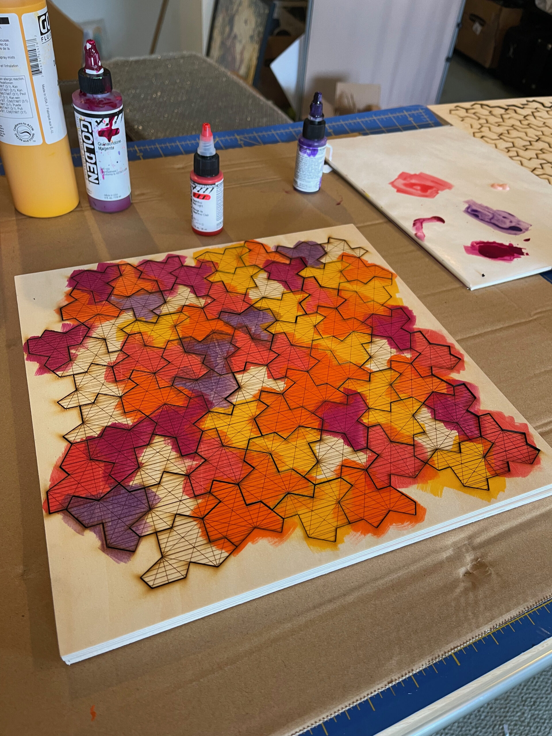 Einstein tiles being painted with Golden acrylics in warm gradient colors