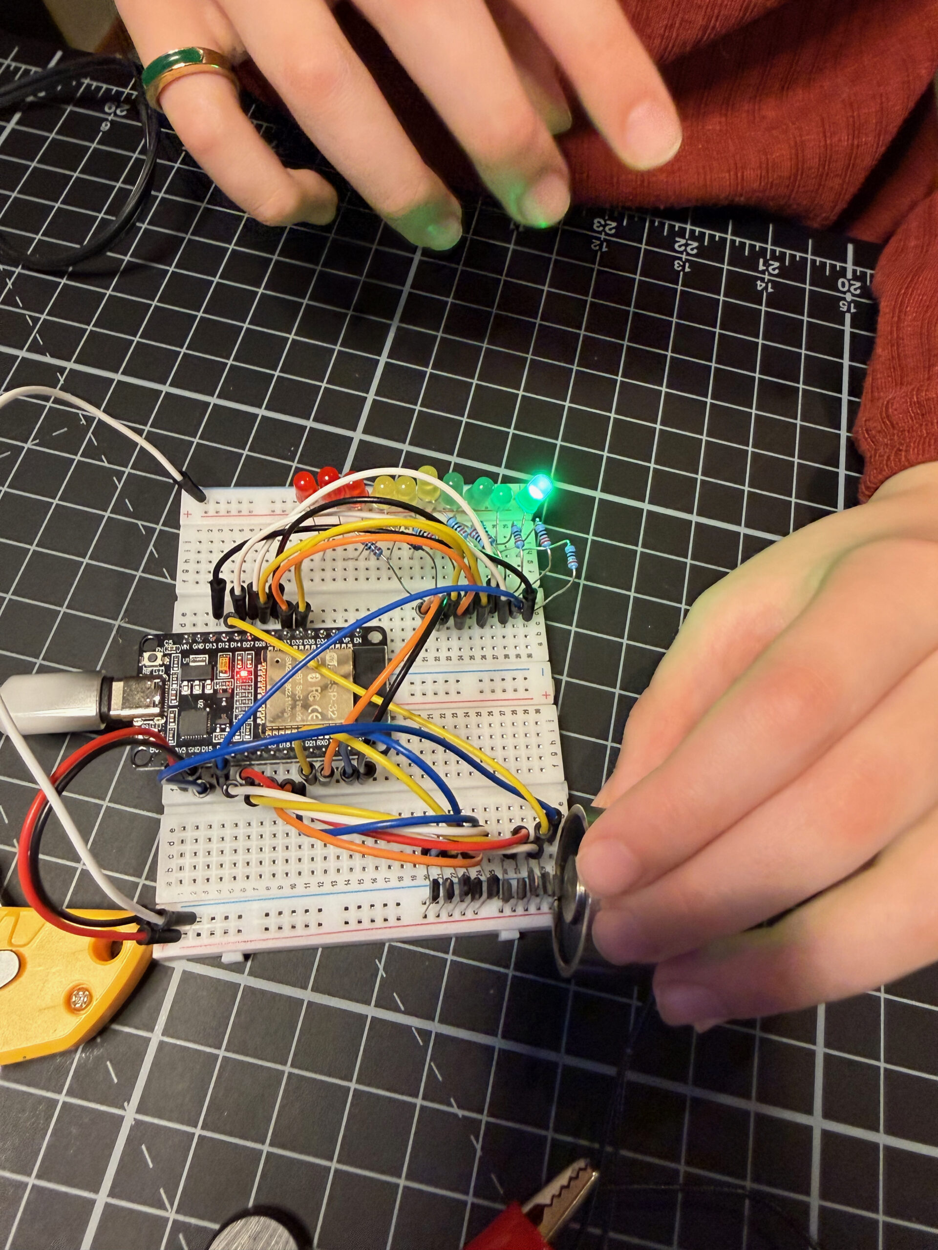 Hand holding a magnet near the sensor, green LEDs lit